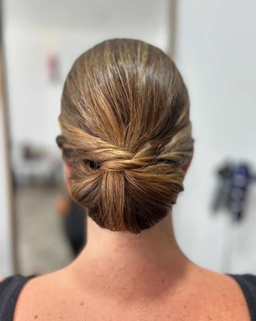 Peinado recogido bajo con nudo central, estilo elegante y pulido de Peluquería y belleza unisex en Yeste